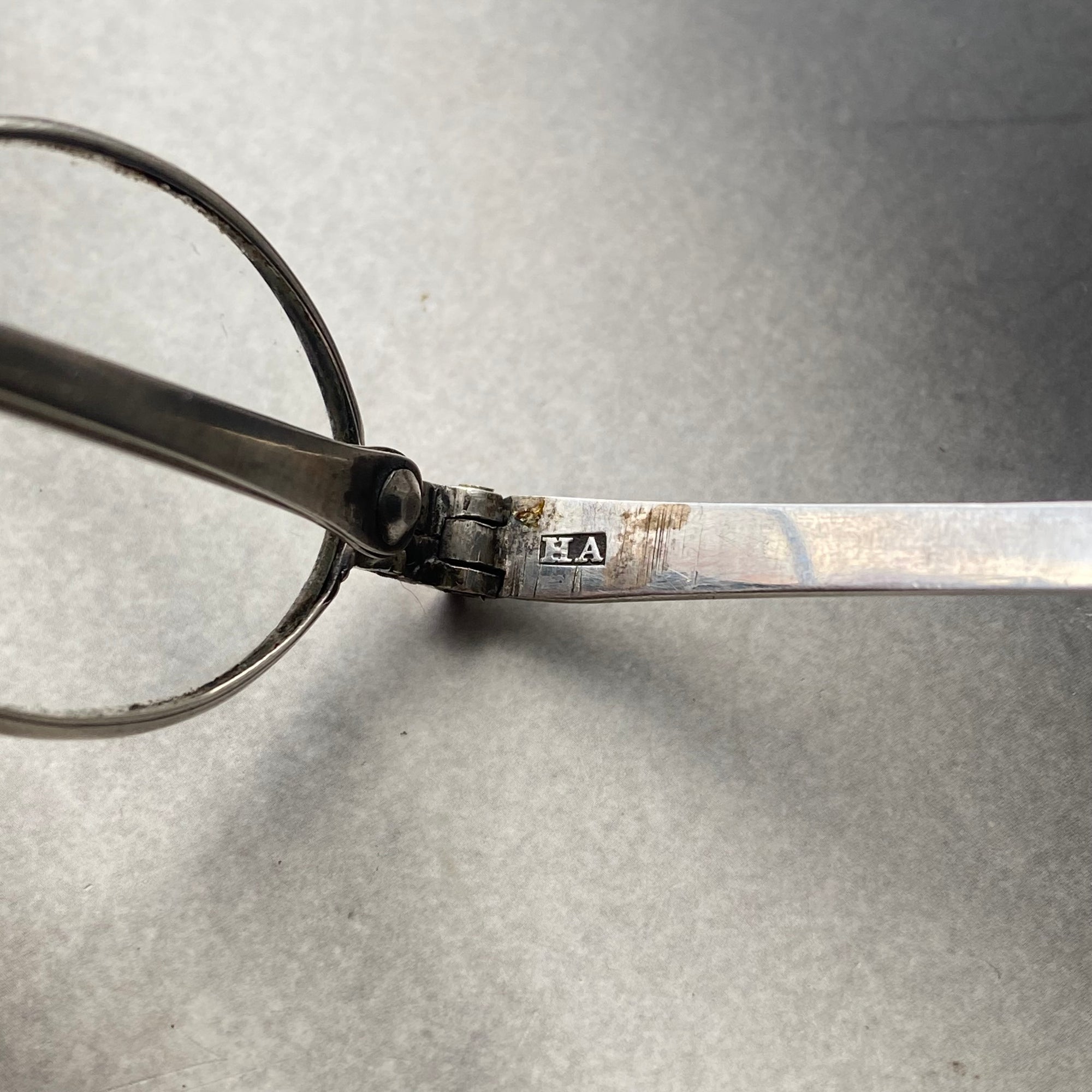 antique eyeglasses with a silver frame on a gray background